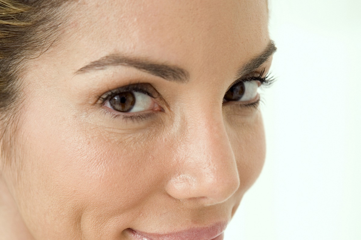 Close-up of a mid adult woman wiping her face with a cotton pad
