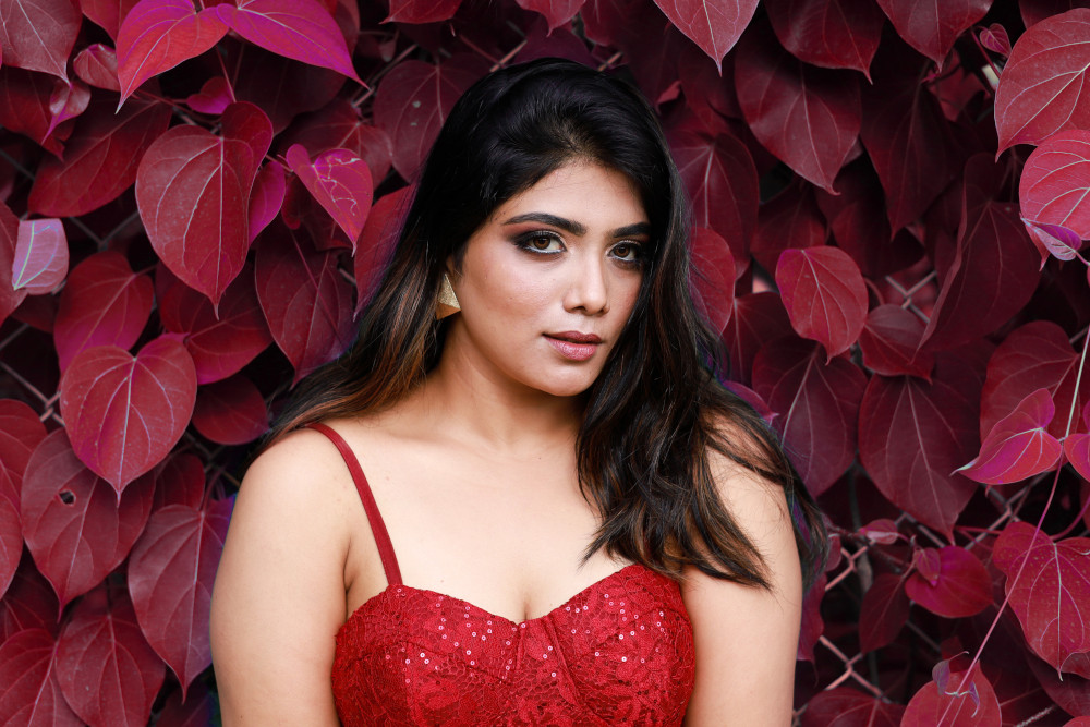 woman next to leafy wall