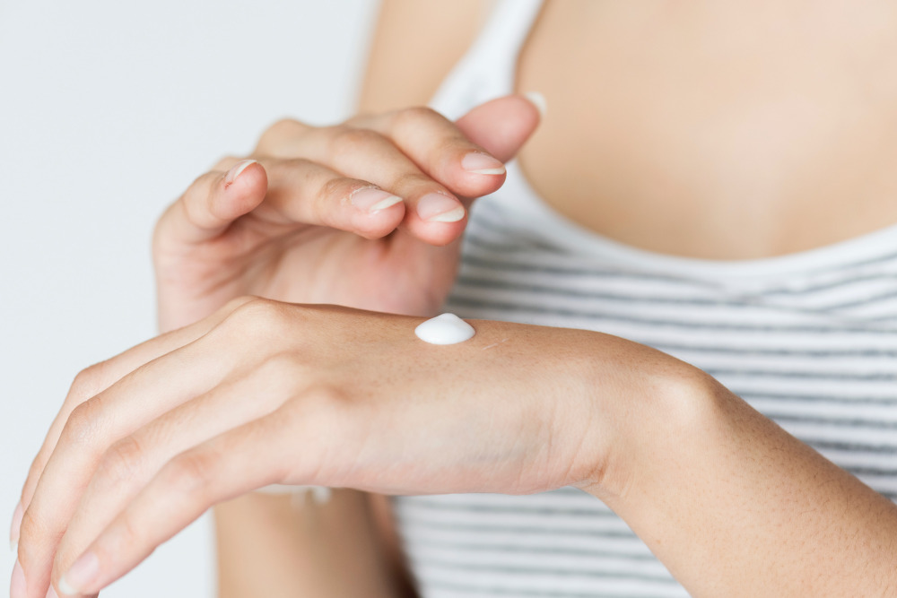 Woman putting lotion on her hand.